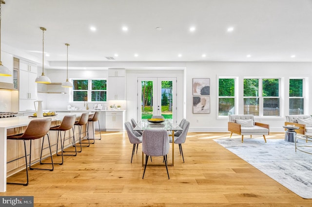 dining area featuring french doors, light wood-type flooring, and plenty of natural light