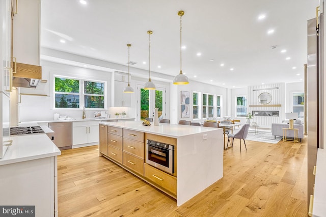 kitchen featuring white cabinetry, a kitchen island, decorative light fixtures, and light wood-type flooring