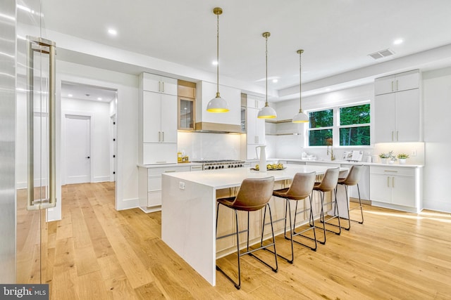 kitchen featuring white cabinets, a center island, light hardwood / wood-style flooring, and a breakfast bar