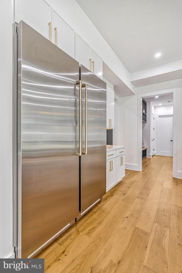 kitchen with high end refrigerator, light hardwood / wood-style floors, and white cabinetry