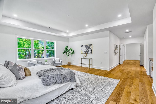 bedroom with a raised ceiling and light hardwood / wood-style floors