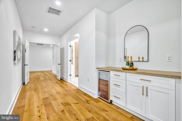 corridor with light wood-type flooring and beverage cooler