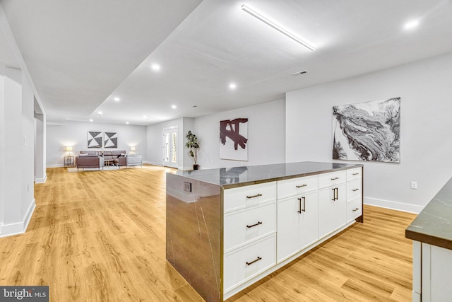 kitchen featuring a center island, dark stone countertops, light hardwood / wood-style flooring, and white cabinets