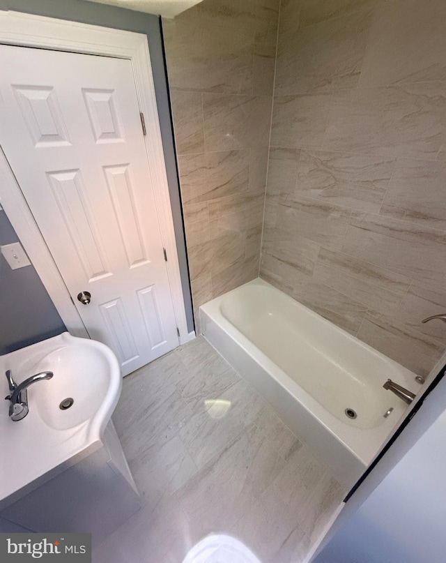 bathroom featuring a tub, sink, and tile walls