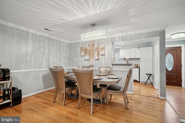 dining space featuring a chandelier, light hardwood / wood-style floors, and ornamental molding