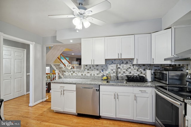 kitchen with backsplash, sink, light hardwood / wood-style flooring, white cabinetry, and stainless steel appliances