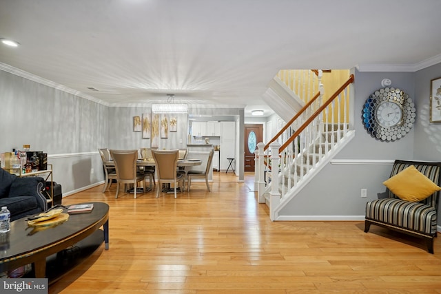 living room featuring a chandelier, crown molding, and light hardwood / wood-style flooring