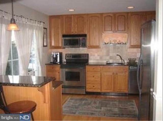 kitchen with pendant lighting, a kitchen breakfast bar, sink, appliances with stainless steel finishes, and kitchen peninsula