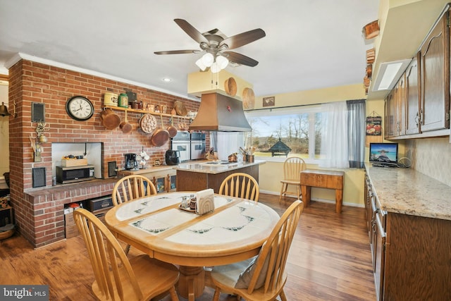 dining area featuring ceiling fan, light hardwood / wood-style floors, and brick wall