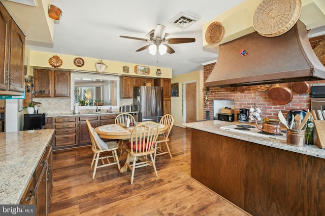 kitchen with appliances with stainless steel finishes, dark hardwood / wood-style flooring, tasteful backsplash, light stone counters, and exhaust hood