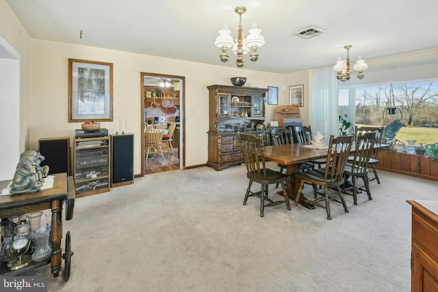 carpeted dining area with a chandelier