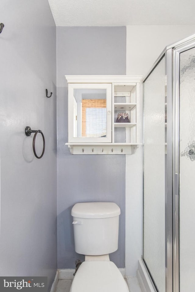 bathroom with toilet and a shower with door