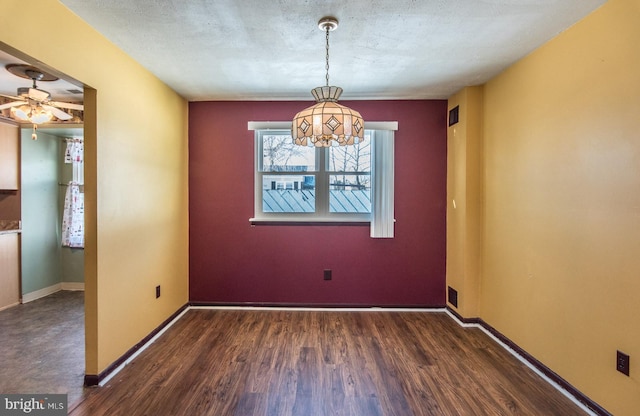 empty room featuring a textured ceiling, ceiling fan, and dark wood-type flooring