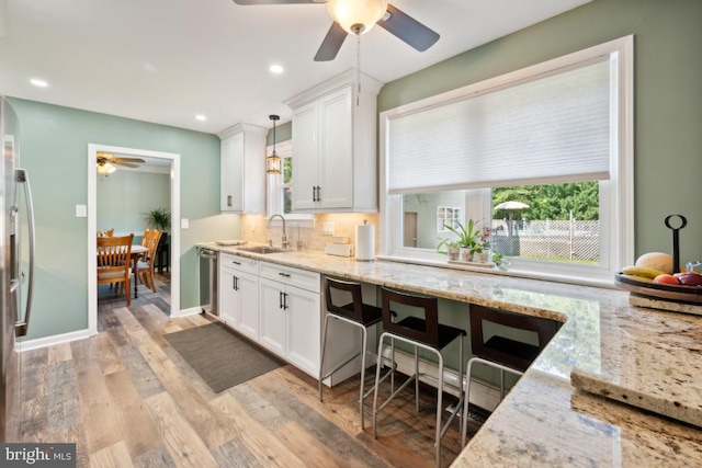 kitchen featuring pendant lighting, light hardwood / wood-style flooring, white cabinetry, and sink