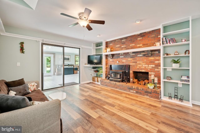 living room featuring a wood stove, ceiling fan, and hardwood / wood-style flooring