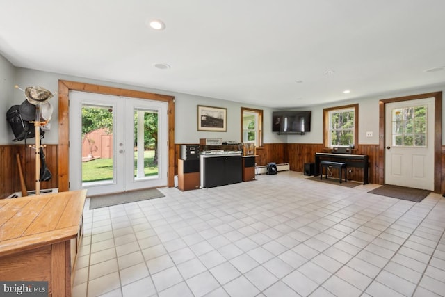 tiled living room with plenty of natural light, wooden walls, and a baseboard radiator