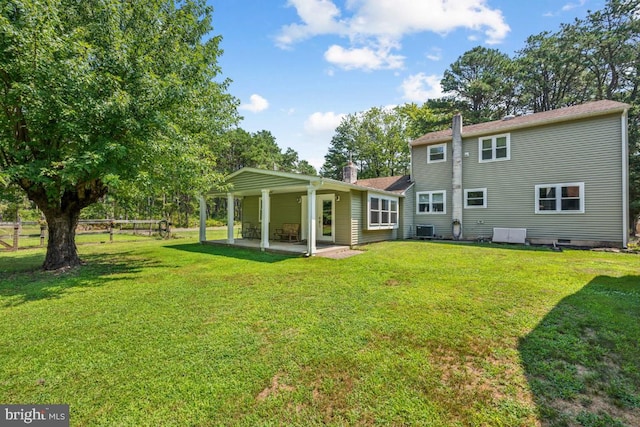 rear view of property with a yard, a patio, and central air condition unit