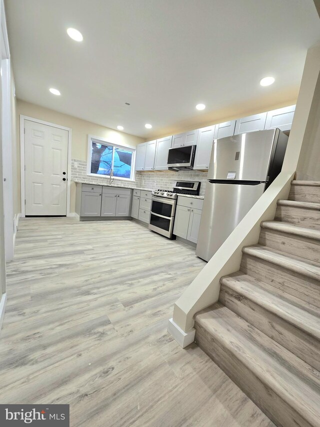 kitchen with stainless steel appliances, light hardwood / wood-style flooring, tasteful backsplash, and sink