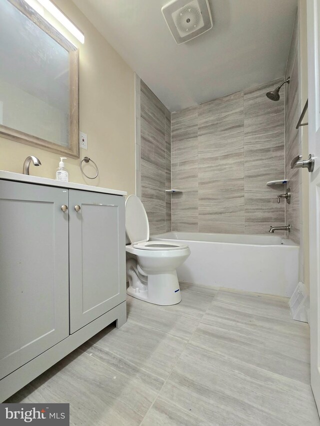 full bathroom with vanity, tiled shower / bath, and toilet