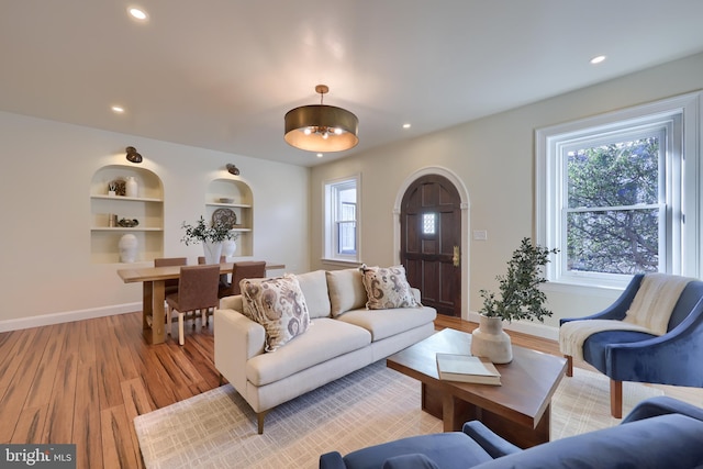 living room featuring built in shelves and light wood-type flooring