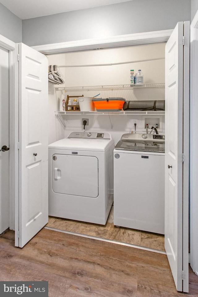 clothes washing area with washing machine and dryer and light wood-type flooring