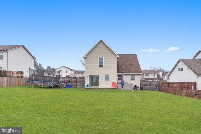 back of property with a yard and a trampoline