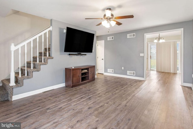 unfurnished living room with ceiling fan with notable chandelier and hardwood / wood-style flooring