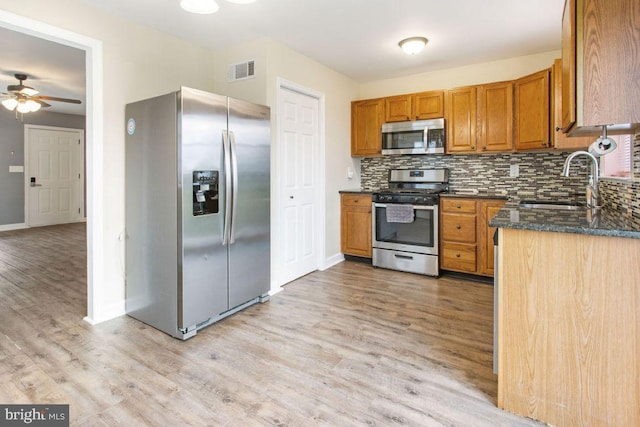 kitchen with sink, ceiling fan, decorative backsplash, light hardwood / wood-style floors, and stainless steel appliances