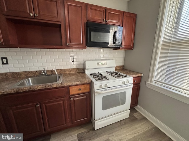 kitchen featuring decorative backsplash, wood-type flooring, white gas stove, and sink