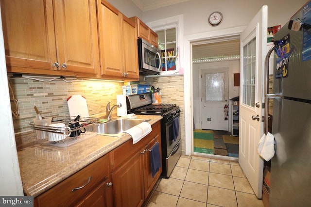 kitchen featuring appliances with stainless steel finishes, backsplash, crown molding, sink, and light tile patterned floors