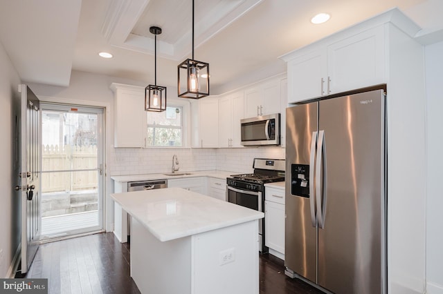 kitchen with white cabinetry, sink, hanging light fixtures, a kitchen island, and appliances with stainless steel finishes