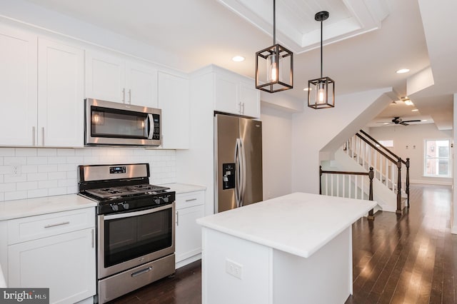 kitchen with ceiling fan, white cabinets, hanging light fixtures, and appliances with stainless steel finishes