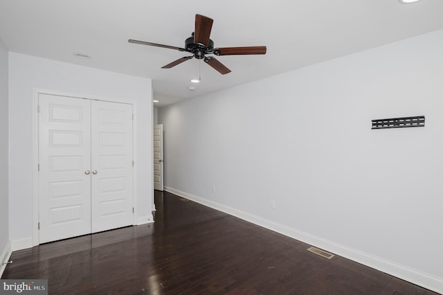 unfurnished bedroom with dark hardwood / wood-style flooring, a closet, and ceiling fan