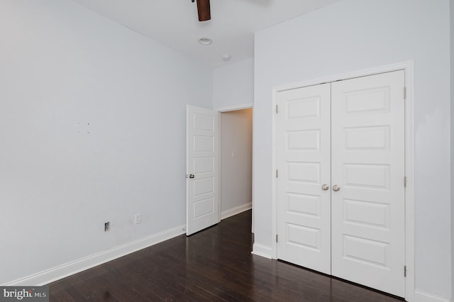 unfurnished bedroom featuring a closet, dark wood-type flooring, and ceiling fan