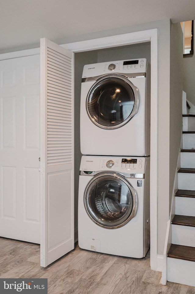 laundry area featuring light hardwood / wood-style flooring and stacked washer and clothes dryer