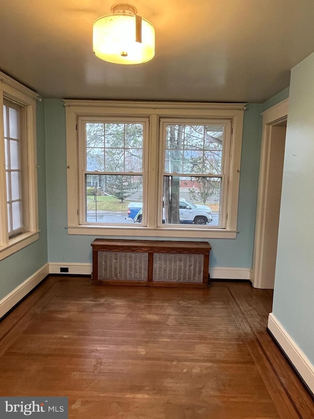 unfurnished room featuring radiator heating unit and hardwood / wood-style floors