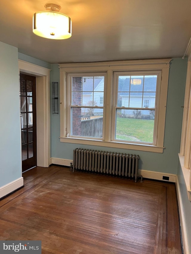 empty room with radiator heating unit, dark wood-type flooring, and french doors