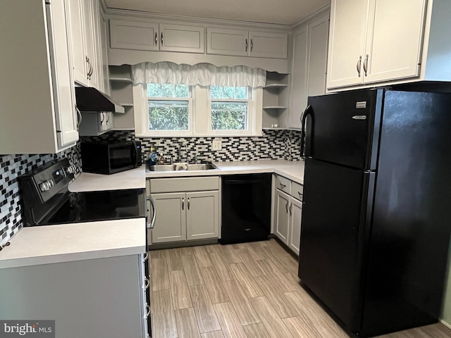 kitchen featuring backsplash, sink, black appliances, and light wood-type flooring