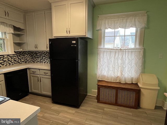 kitchen featuring light wood-type flooring, backsplash, white cabinetry, and black appliances