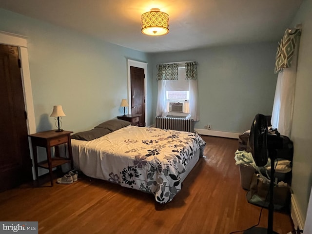 bedroom with cooling unit, radiator, and dark wood-type flooring