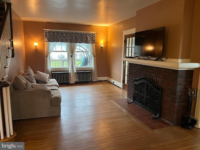 living room featuring a fireplace, radiator heating unit, and hardwood / wood-style flooring