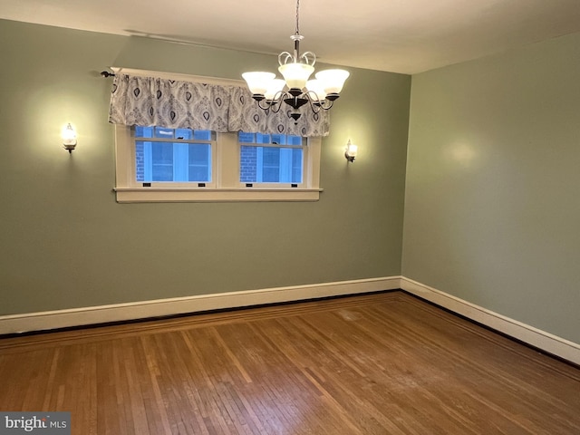 unfurnished room with hardwood / wood-style flooring and a notable chandelier