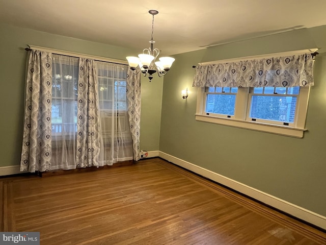 spare room with a chandelier and hardwood / wood-style floors