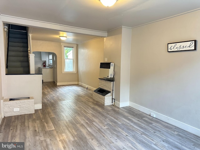 unfurnished living room with hardwood / wood-style flooring, ornamental molding, and heating unit