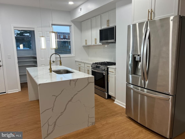 kitchen featuring white cabinetry, sink, hanging light fixtures, a center island with sink, and appliances with stainless steel finishes