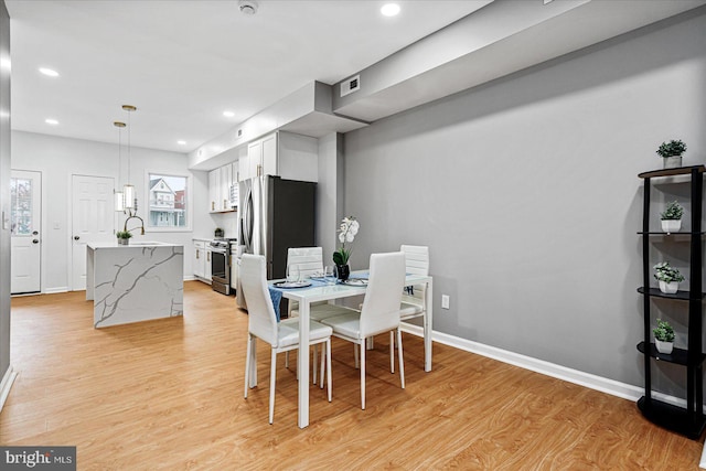 dining space with light hardwood / wood-style floors and sink