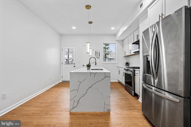 kitchen with a center island with sink, white cabinets, sink, appliances with stainless steel finishes, and light hardwood / wood-style floors