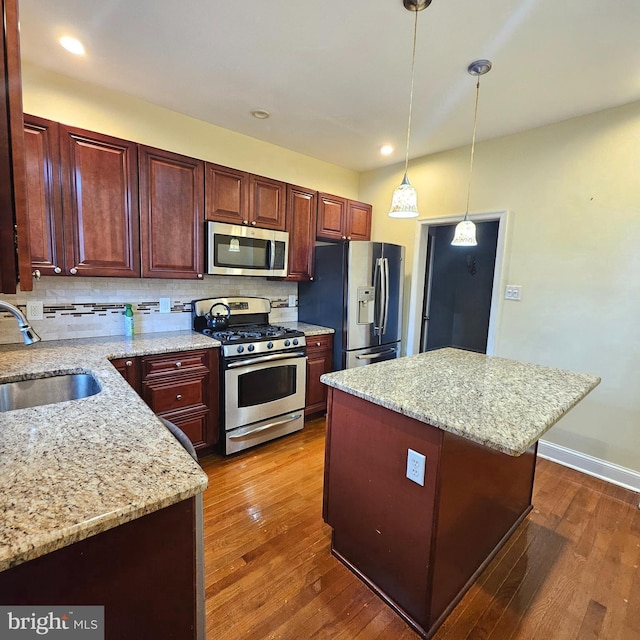 kitchen with stainless steel appliances, a kitchen island, dark hardwood / wood-style floors, and sink