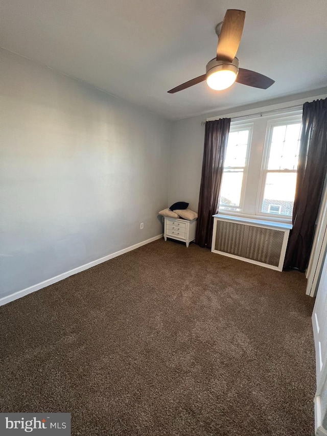 empty room with radiator heating unit, dark carpet, and ceiling fan