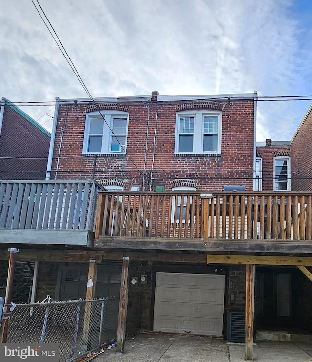 rear view of property featuring a garage and a deck